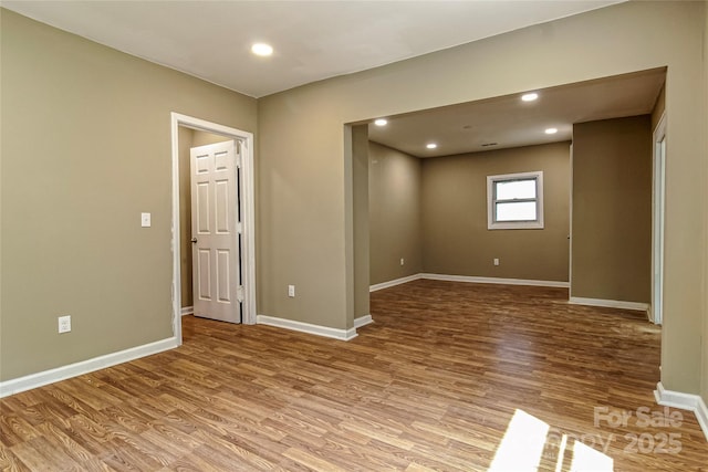 spare room with baseboards, recessed lighting, and wood finished floors