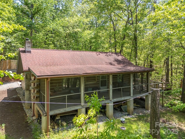 84 Bishop Ln, Mill Spring, NC 28756 - back of house with a sunroom, a shingled roof, a wooded view, and a chimney