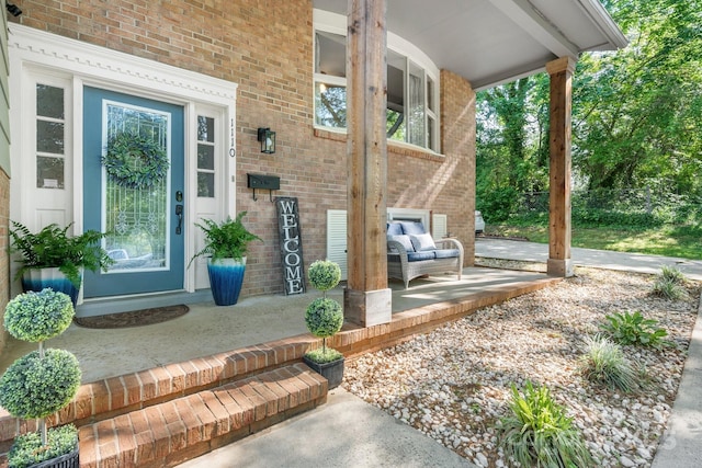 doorway to property with a porch and brick siding