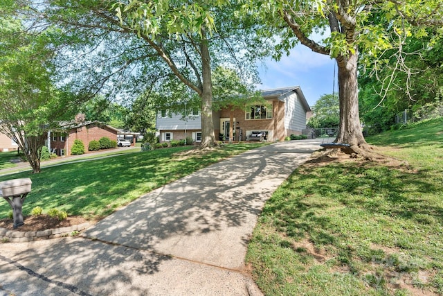 bi-level home with concrete driveway, brick siding, and a front yard