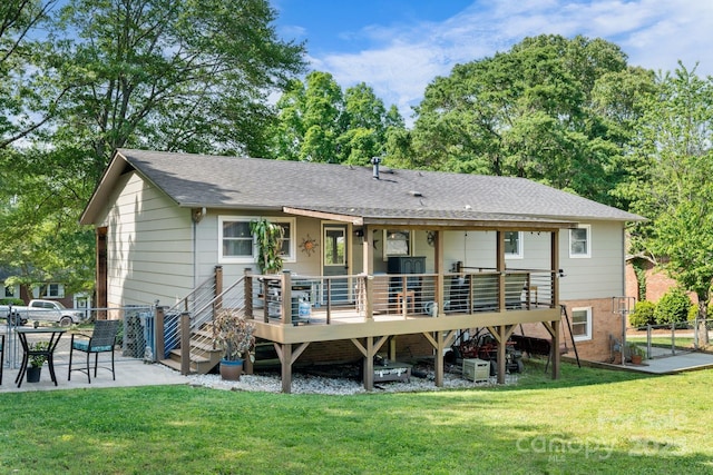 rear view of house with roof with shingles, a lawn, a wooden deck, a patio area, and fence
