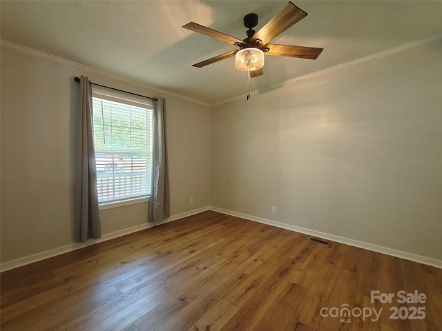 empty room featuring ornamental molding, wood-type flooring, a ceiling fan, and visible vents