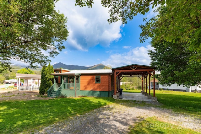 214 Pike Pt, Waynesville, NC 28785 - view of front facade with a front lawn, covered porch, dirt driveway, a mountain view, and a carport