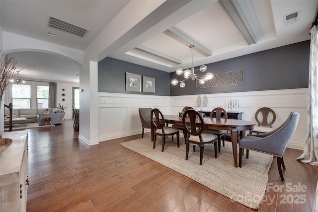 dining space with visible vents, arched walkways, beam ceiling, and wood finished floors