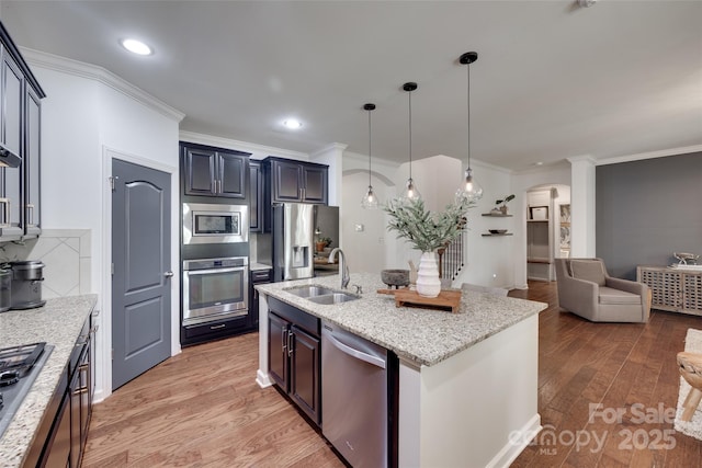 kitchen with a sink, crown molding, stainless steel appliances, and open floor plan