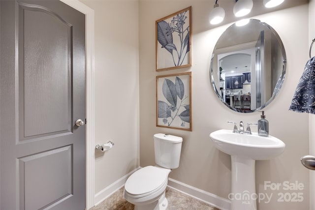 half bath featuring a sink, baseboards, and toilet