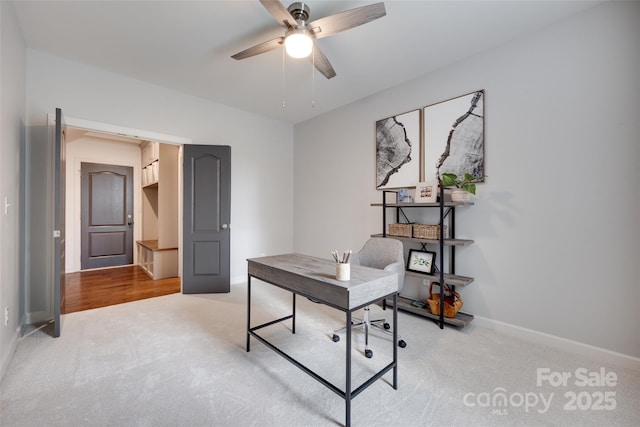 office featuring baseboards, ceiling fan, and light carpet