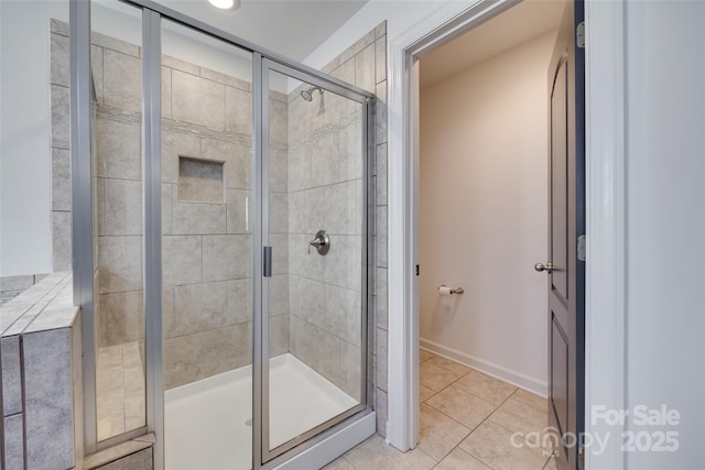 bathroom with tile patterned flooring, baseboards, and a shower stall