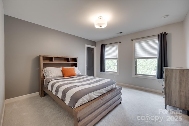 bedroom with baseboards, visible vents, and light carpet