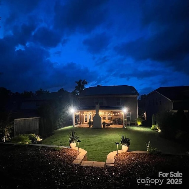 back of house at twilight with a lawn