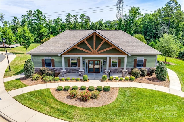 view of front of property with stone siding, roof with shingles, french doors, and a front yard