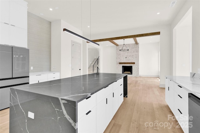 124 Clipper Ln, Mooresville, NC 28117 - kitchen with modern cabinets, light wood-type flooring, beam ceiling, dark stone counters, and a spacious island
