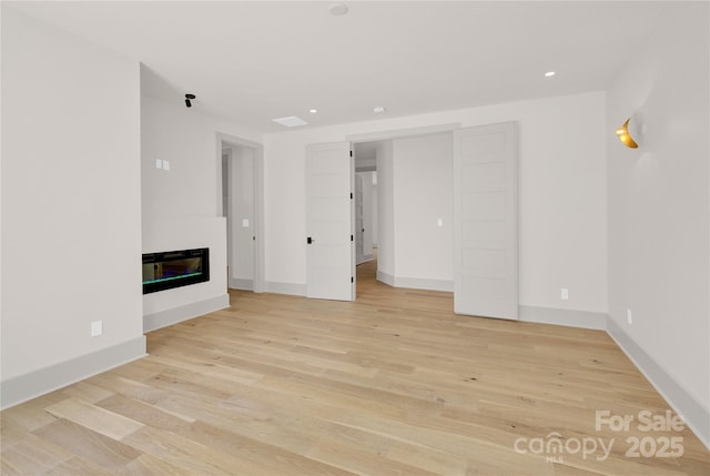 124 Clipper Ln, Mooresville, NC 28117 - unfurnished living room featuring light wood finished floors, a glass covered fireplace, baseboards, and recessed lighting