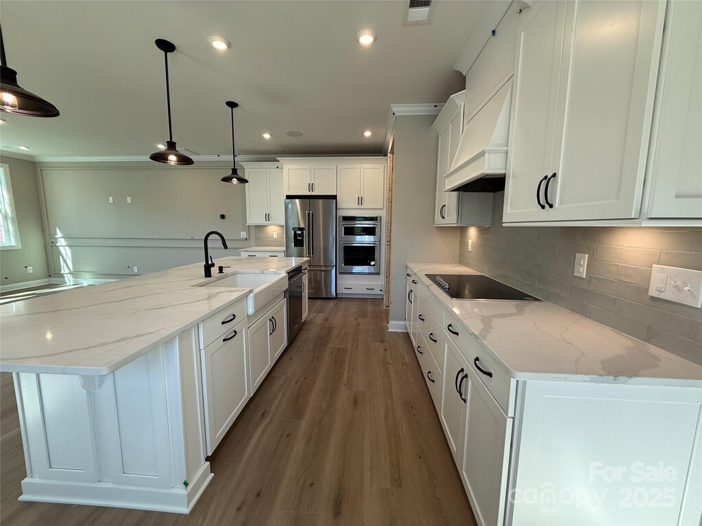 kitchen featuring a sink, premium range hood, black appliances, visible vents, and backsplash