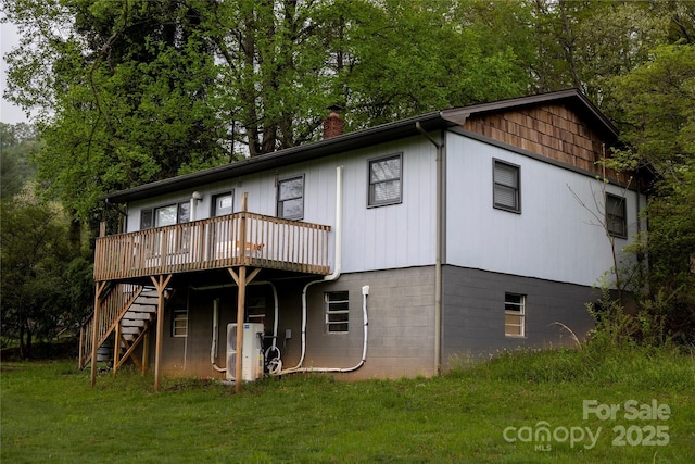 back of property with ac unit, a deck, stairway, a chimney, and a lawn