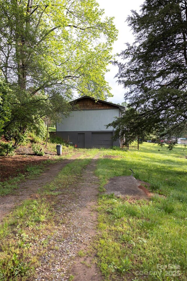 view of property exterior with a garage, an outbuilding, a pole building, and driveway