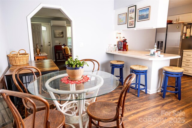 dining room featuring arched walkways, an AC wall unit, and dark wood-style floors
