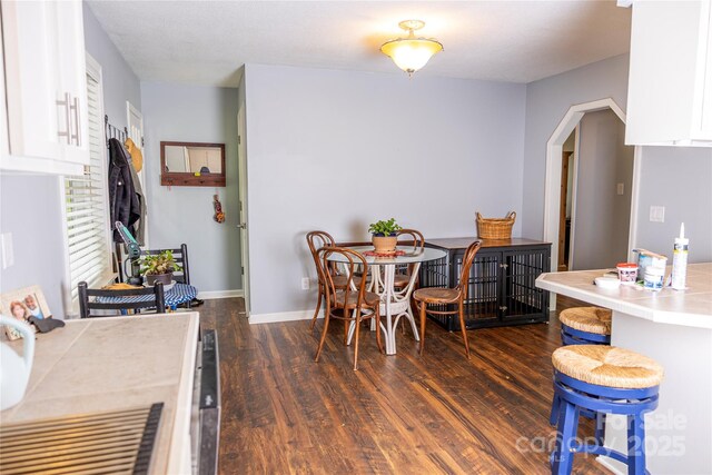dining space with baseboards and dark wood-style flooring