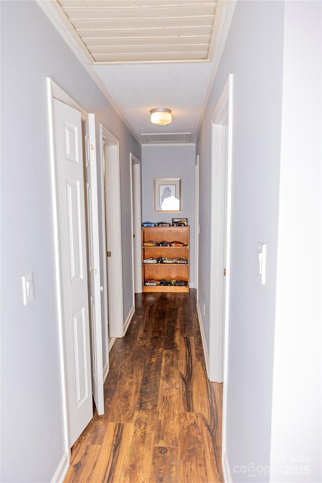 corridor featuring baseboards, ornamental molding, and wood finished floors