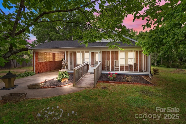 rear view of property with a lawn, a carport, concrete driveway, and brick siding