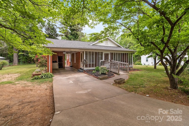 view of front of property featuring concrete driveway, an attached carport, a shingled roof, and a front lawn