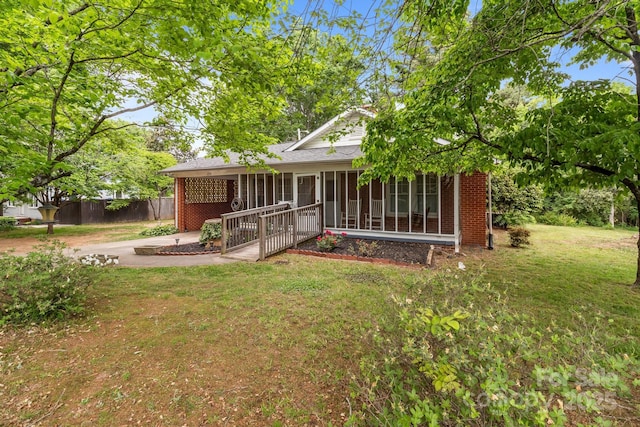 view of front of house with fence, a sunroom, a front lawn, and brick siding