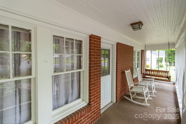sunroom with carpet flooring, brick wall, and wooden ceiling