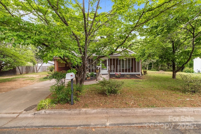 obstructed view of property featuring a sunroom, a front lawn, and fence