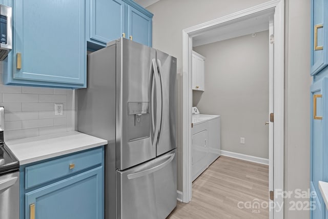 kitchen featuring decorative backsplash, stainless steel refrigerator with ice dispenser, light countertops, separate washer and dryer, and blue cabinets