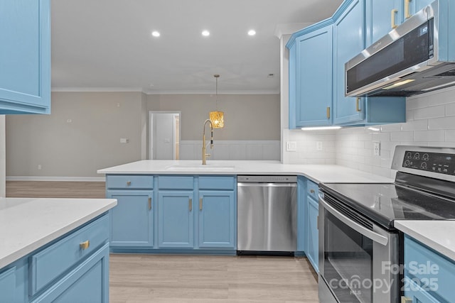 kitchen featuring crown molding, a sink, blue cabinetry, stainless steel appliances, and a peninsula