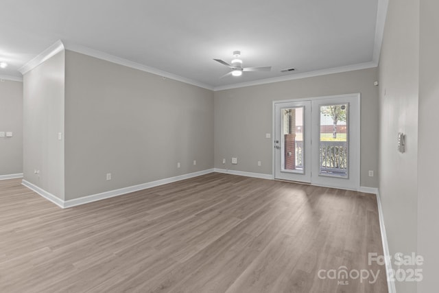 empty room featuring crown molding, baseboards, ceiling fan, and light wood-style floors