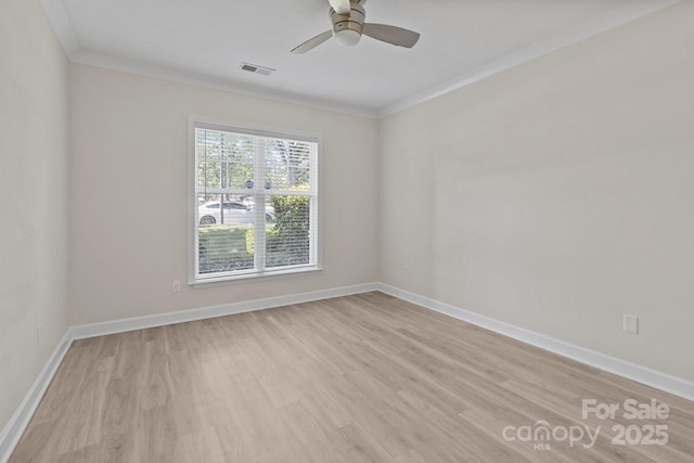 spare room with visible vents, ornamental molding, baseboards, ceiling fan, and light wood-type flooring