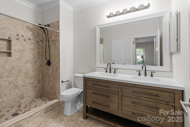 bathroom with toilet, a tile shower, and a sink