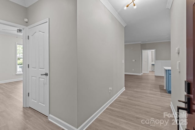 corridor with crown molding, baseboards, and light wood-type flooring