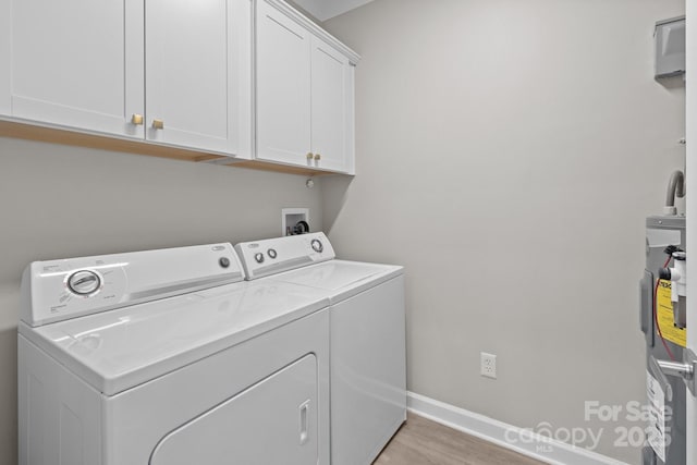 laundry room featuring light wood finished floors, baseboards, washer and clothes dryer, cabinet space, and water heater