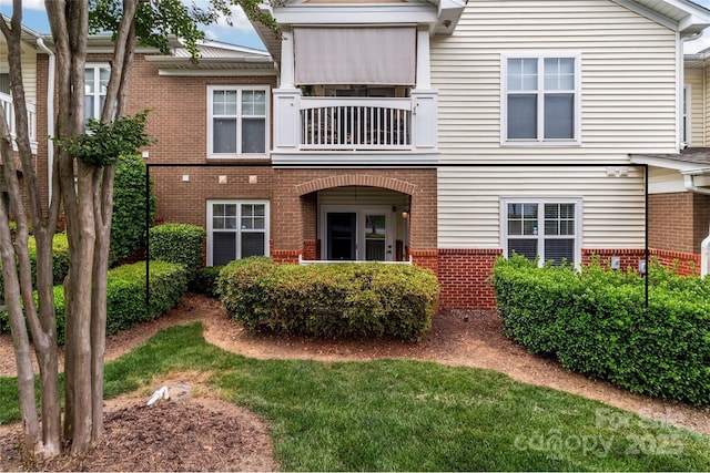 view of property featuring brick siding and a balcony