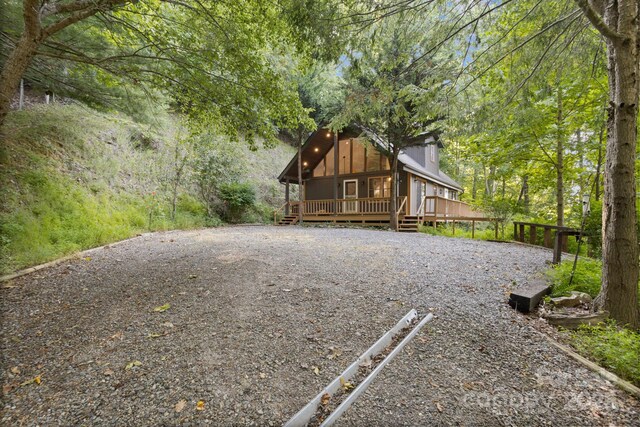 view of front facade featuring a wooded view and a deck