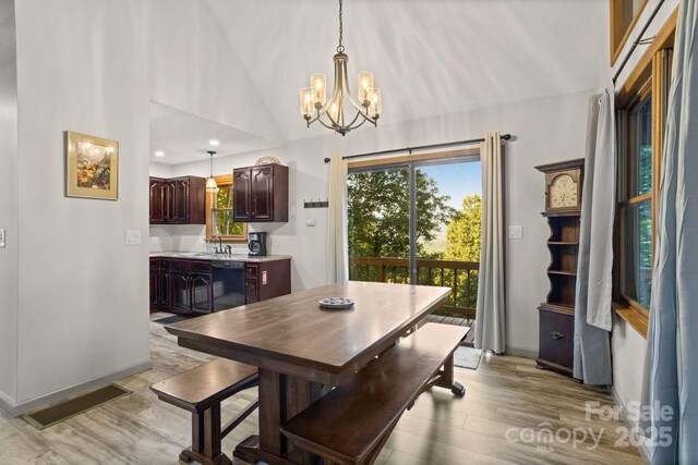 dining space featuring visible vents, an inviting chandelier, baseboards, light wood-style floors, and vaulted ceiling
