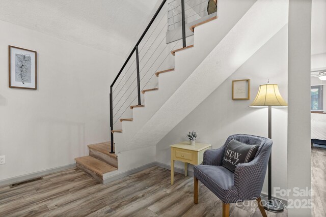 staircase with visible vents, baseboards, and wood finished floors