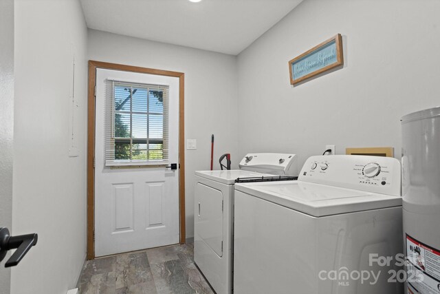 laundry area with laundry area, washer and dryer, baseboards, stone finish flooring, and water heater