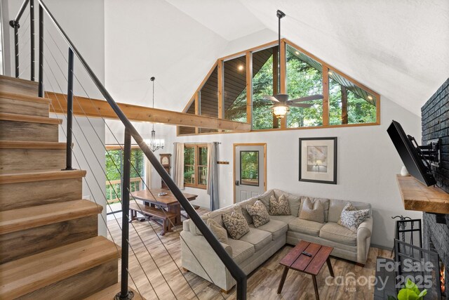 living room with light wood-style floors, ceiling fan with notable chandelier, a wealth of natural light, and stairway