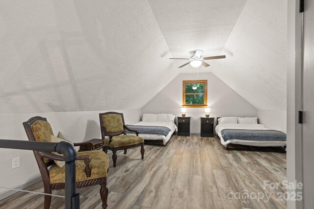 bedroom featuring a ceiling fan, lofted ceiling, a textured ceiling, and wood finished floors