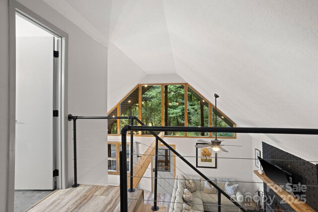 stairway featuring ceiling fan, wood finished floors, and lofted ceiling