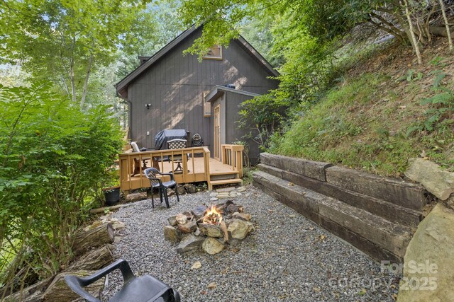 back of house featuring a fire pit and a wooden deck