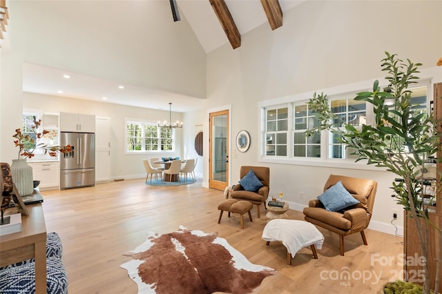 living area featuring light wood-style floors, high vaulted ceiling, baseboards, beamed ceiling, and an inviting chandelier