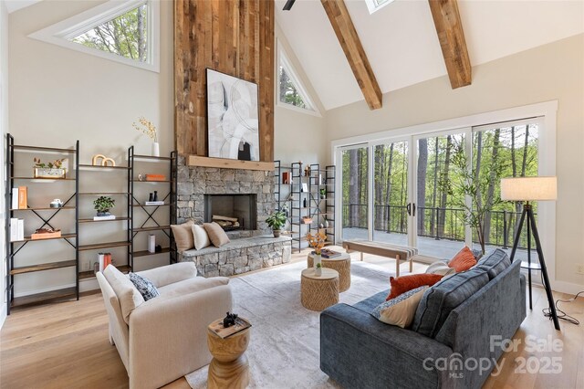 living area with beam ceiling, wood finished floors, a fireplace, baseboards, and high vaulted ceiling
