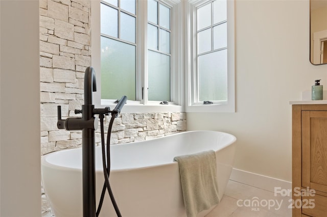 full bathroom with baseboards, a freestanding bath, plenty of natural light, and tile patterned flooring
