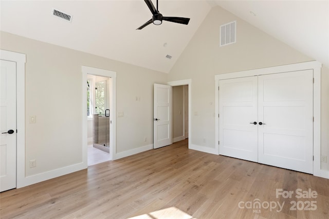 unfurnished bedroom with visible vents, light wood-style flooring, connected bathroom, and high vaulted ceiling