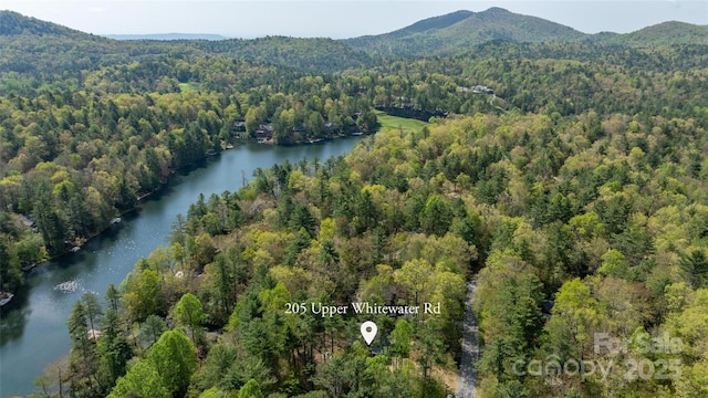 aerial view featuring a water and mountain view and a forest view