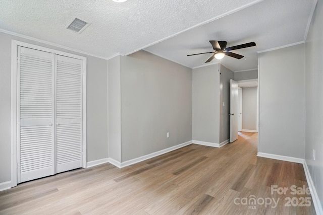 unfurnished bedroom with crown molding, visible vents, wood finished floors, and a closet
